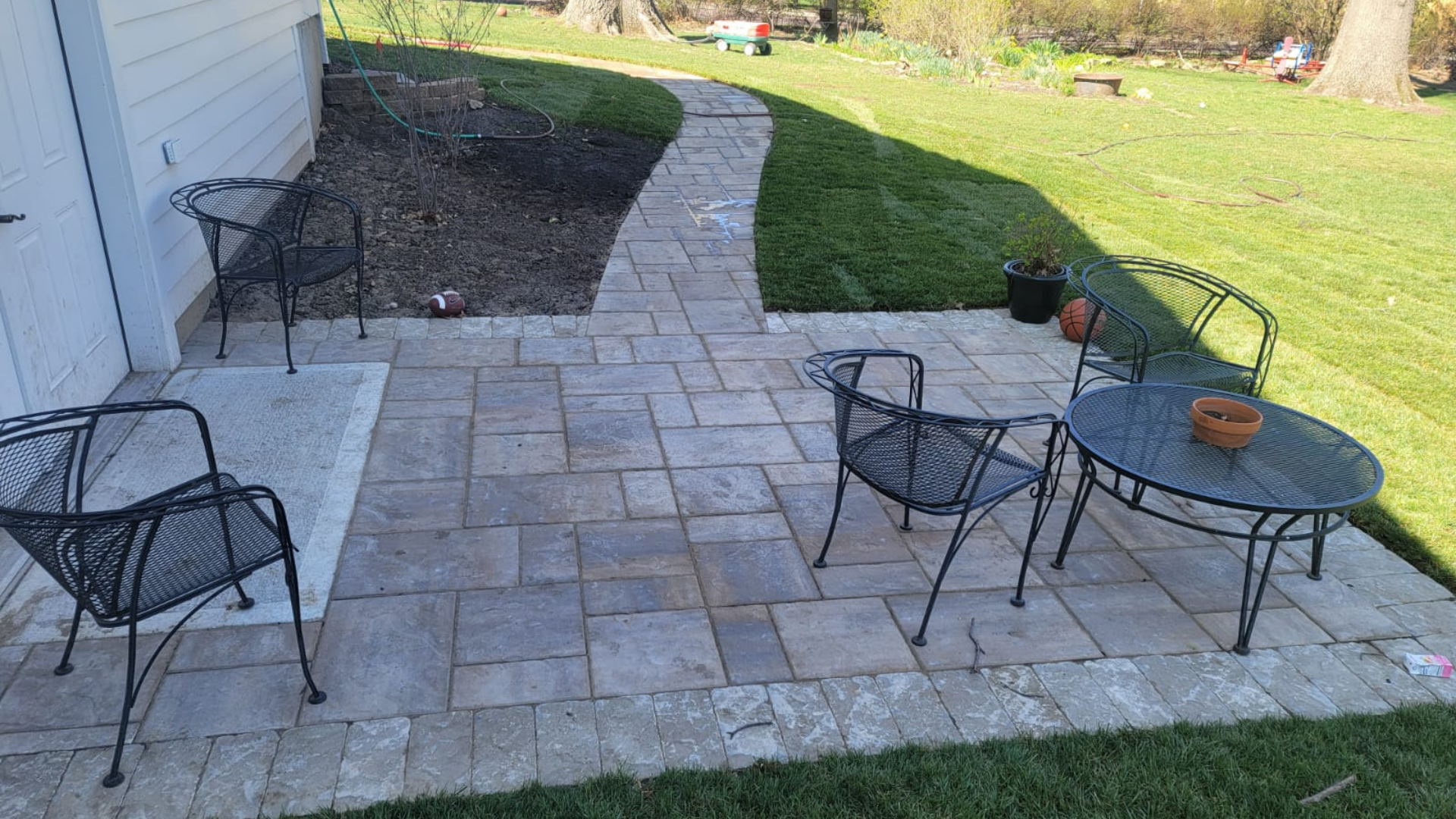 Backyard paver patio with curved walkway and lawn area in Overland Park, Kansas.
