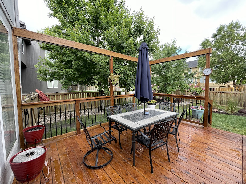 Well-maintained backyard lawn with fence line landscape bed, evergreen shrubs, decorative rock, and clean grass in Leawood Kansas