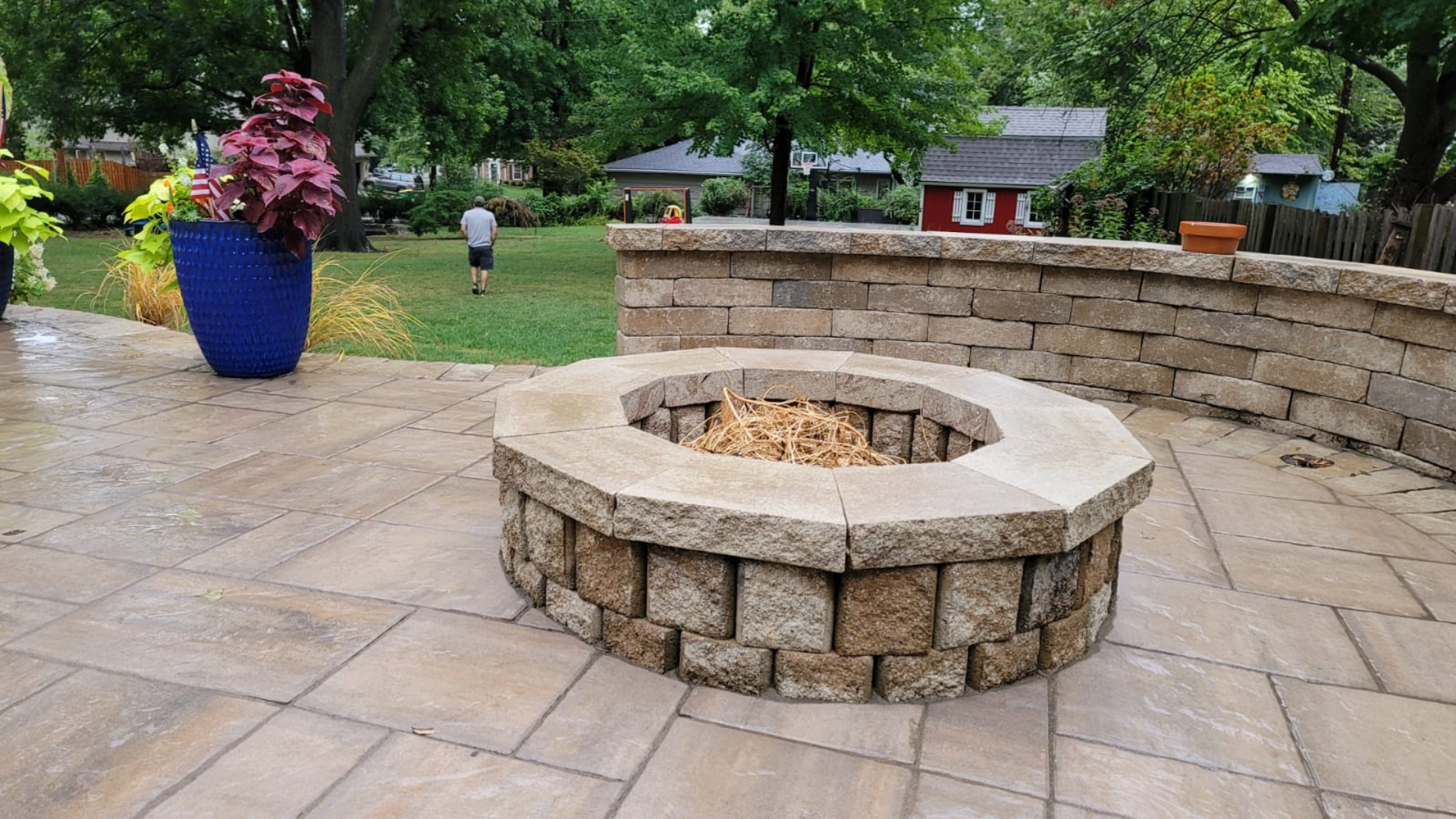 Custom paver patio with fire pit and stone seating wall in Overland Park, Kansas backyard.