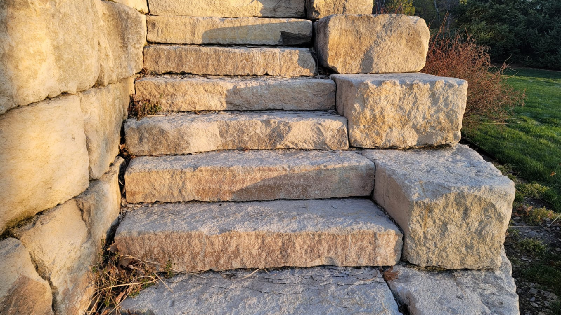 Natural stone steps built into a retaining wall with large stone blocks.