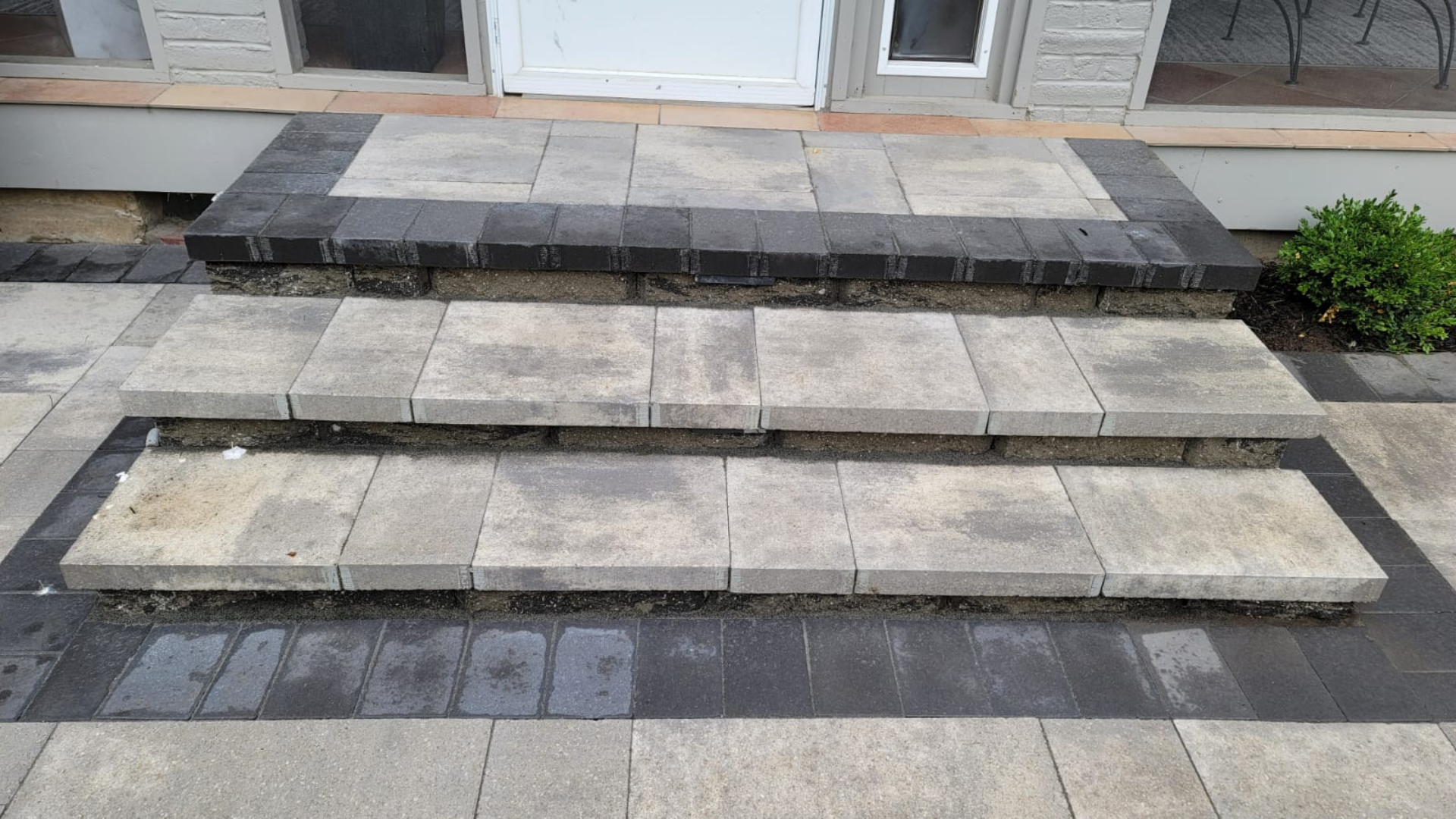 Close-up of block retaining wall steps between two stone retaining walls.