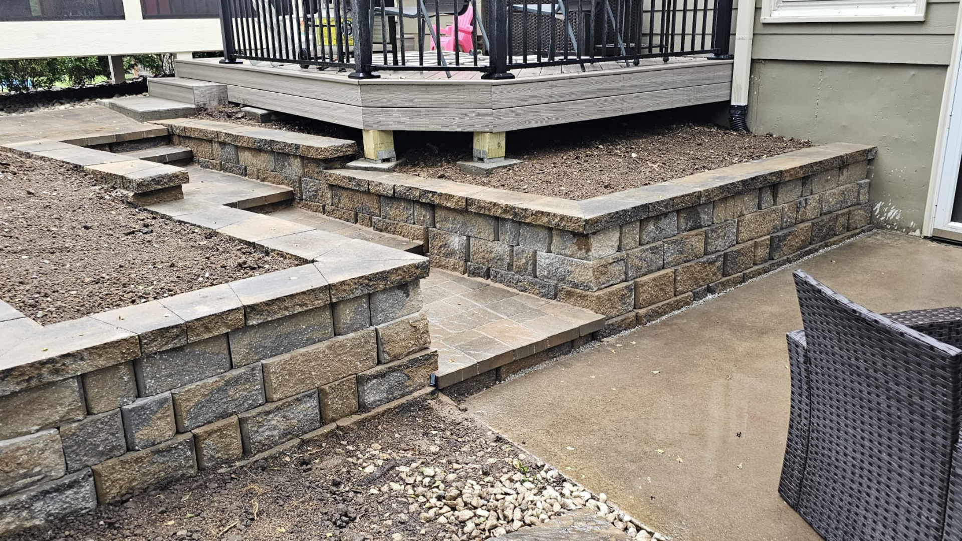 Stone retaining wall with steps, patio landing, and raised deck area.