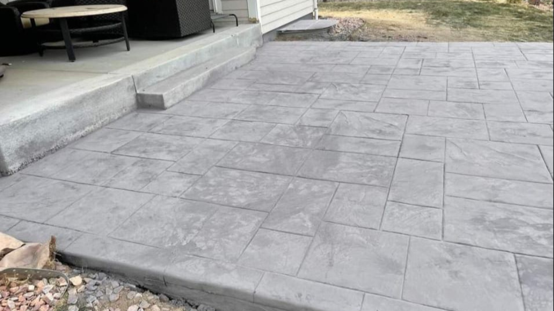 Large stamped concrete patio with decorative stone pattern beside a home.