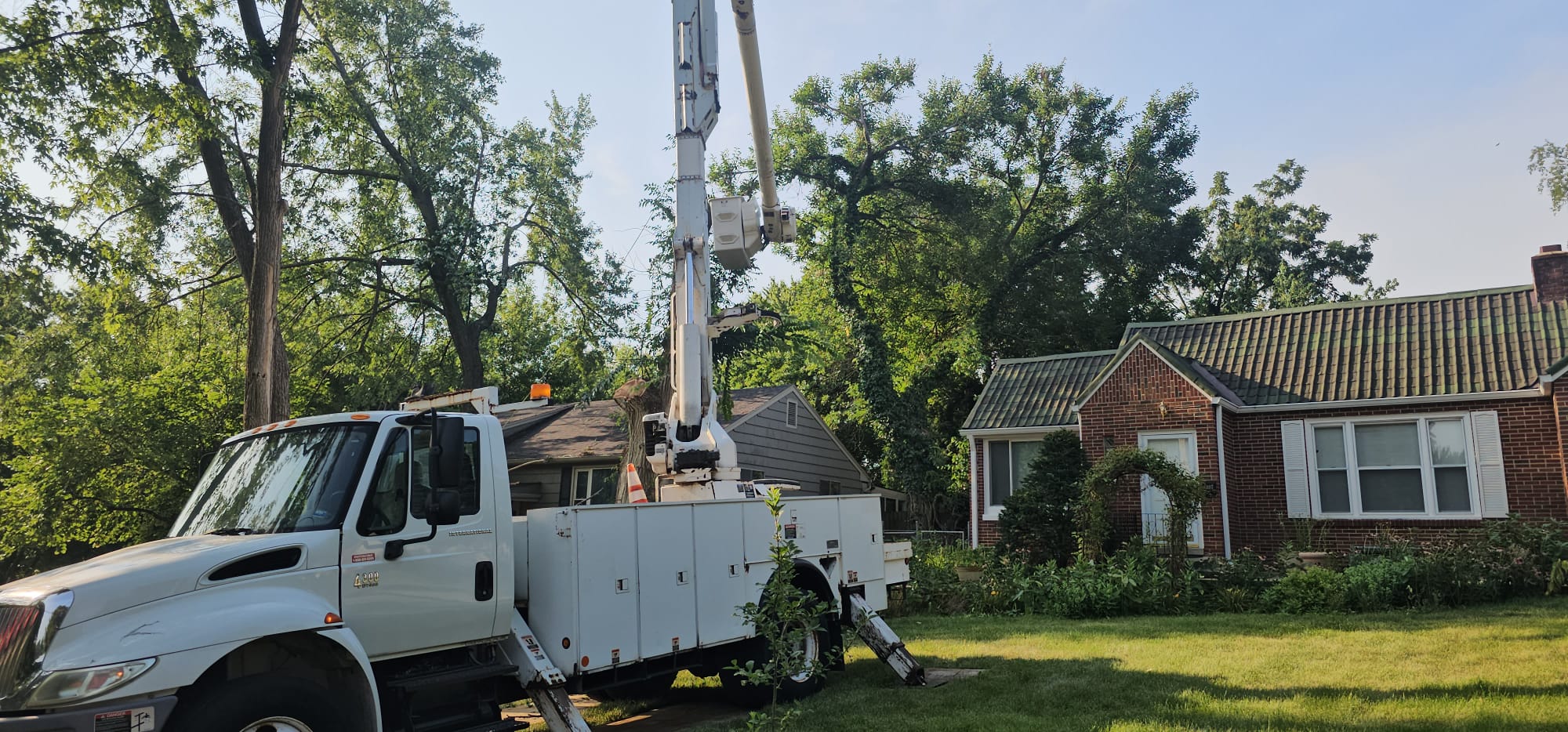Tree service bucket truck working near a residential home in Kansas City to trim and maintain large trees around the property.