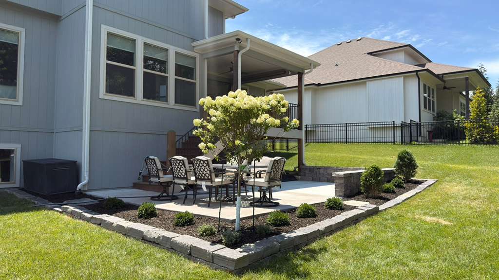 Fence Line Landscape Bed and Lawn Care in Leawood Kansas Well-maintained backyard lawn with fence line landscape bed, evergreen shrubs, decorative rock, and clean grass in Leawood Kansas
