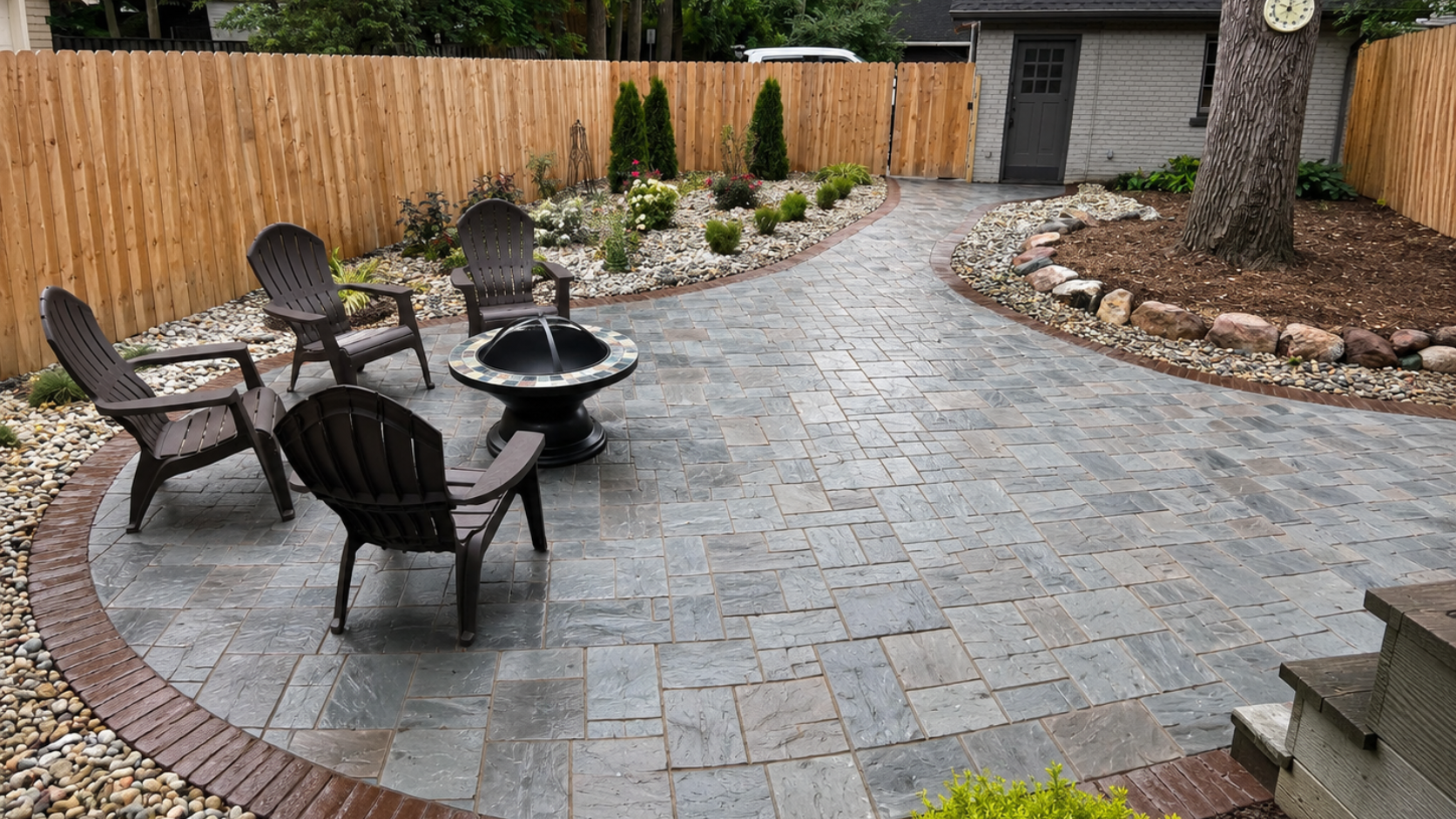 Paver patio with fire pit, Adirondack chairs, landscaped beds, river rock, privacy fence, and backyard walkway example