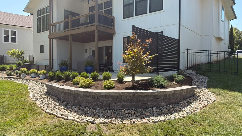 Backyard retaining wall with decorative rock and new landscape plantings