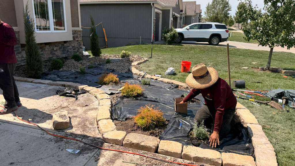 Mountain Landscaping crew installing a stone-edged landscape bed with shrubs and decorative rock