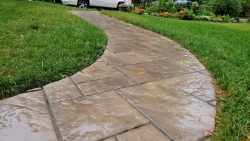 A curved paver walkway adds movement and curb appeal to the landscape. Curved paver walkway surrounded by green grass and front yard landscaping.