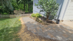 A paver walkway and retaining wall add structure to this side yard landscape. Paver walkway with retaining wall, mulch bed, shrubs, and side yard landscaping.